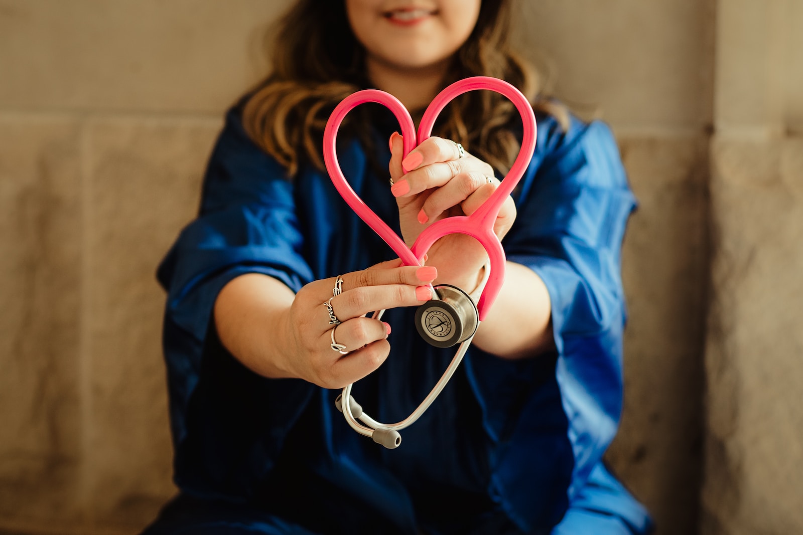 girl in blue jacket holding stethoscope in the shape of a heart